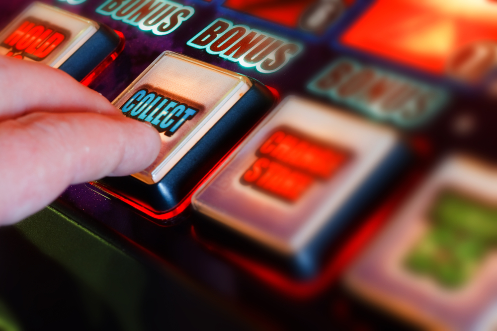 finger pressing collect button on slot machine