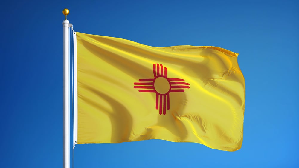 New Mexico flag on pole against blue sky backdrop